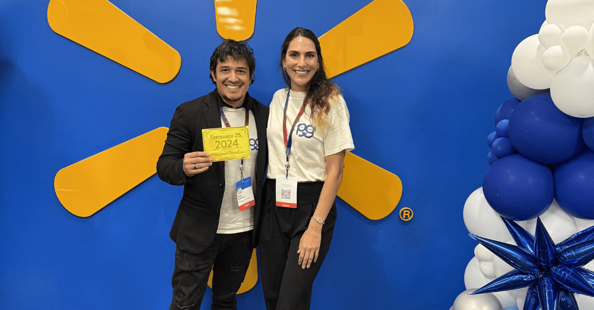 Team members, Janan and Cesar, standing in front of a Walmart logo backdrop holding their golden ticket from walmart