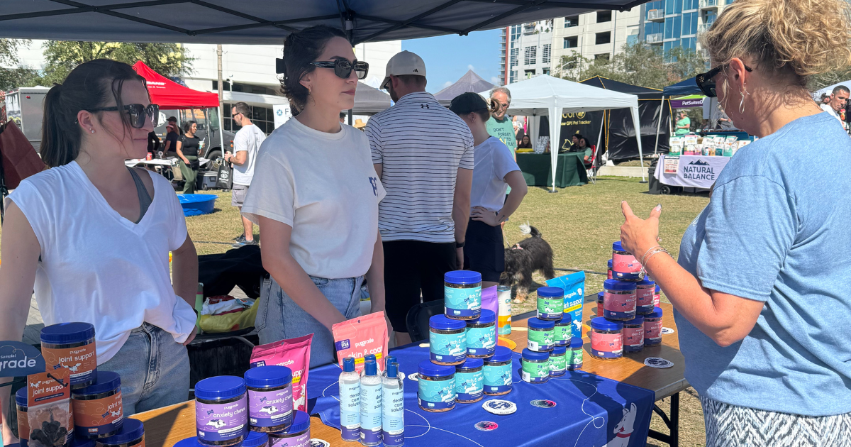 PupGrade team members talking with a woman at booth